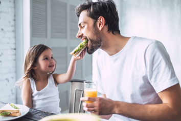Child giving father a bite of her sandwich
