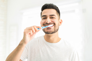 Man smiling while brushing his teeth