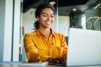Woman smiling while working on laptop in office