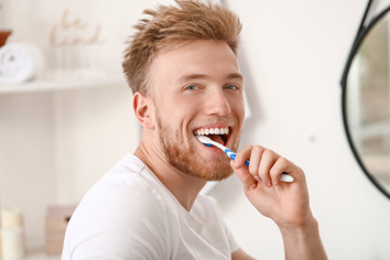 a young man brushing his teeth at home