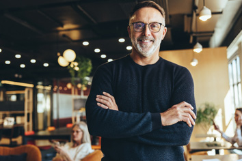 a smiling man with glasses on standing in a restaurant