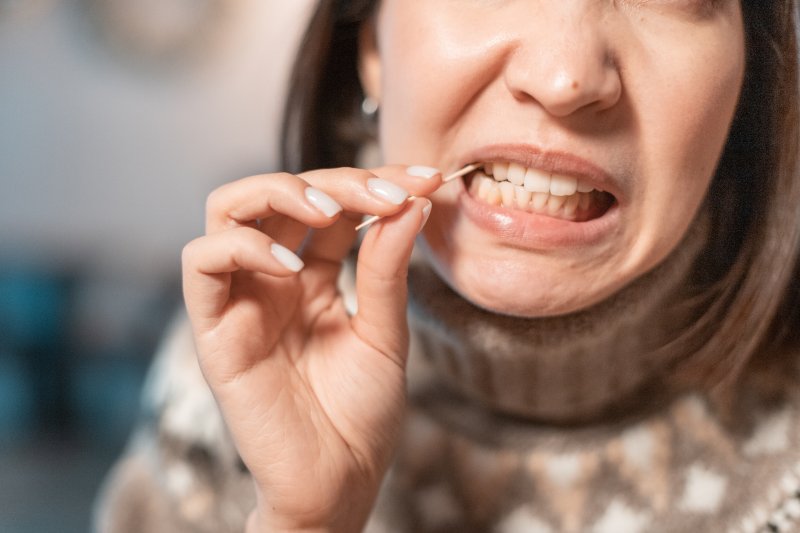 A woman using a toothpick to clean between her teeth
