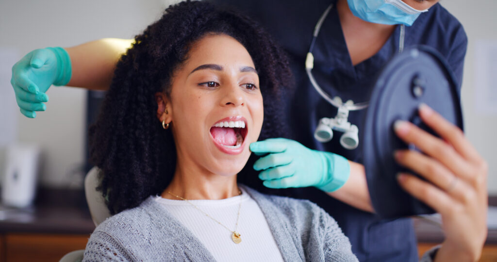 Patient checking new dental crowns in mirror at dentist